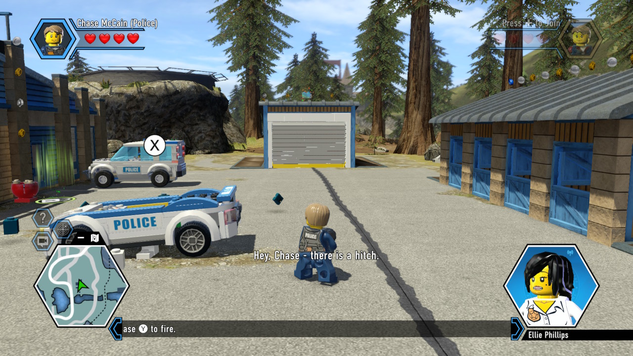 Eine Lego-Polizeifigur auf einem Hof. Links zwei Lego-Polizeifahrzeuge. Eines davon ist kaputt.