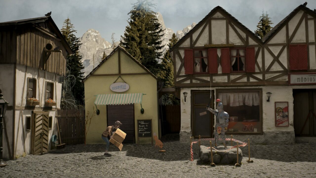 Ein mittelalterlich anmutender Platz mit drei Häusern. Davor eine Ritterrüstung, die auf einem Podest aus Stein steht. Ein Mann hebt einen leeren Karton.