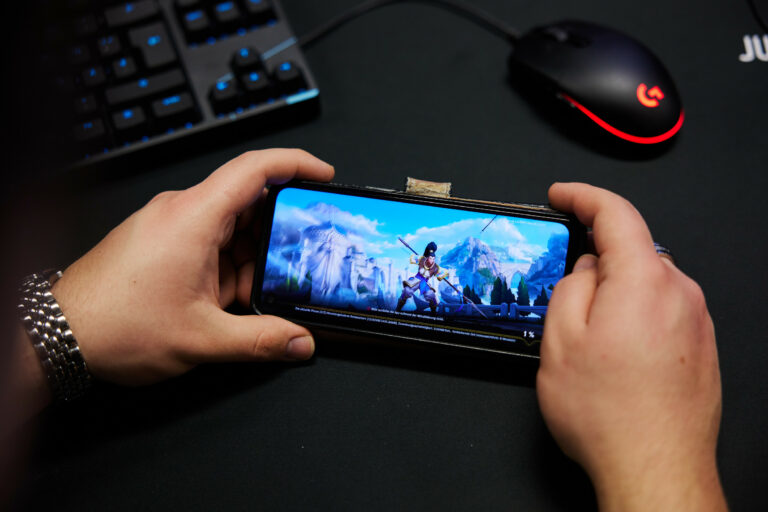 Jugendlicher hält ein Smartphone, auf dem ein Handyspiel läuft.