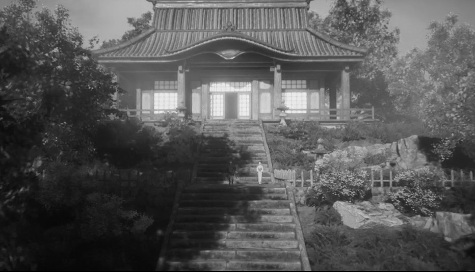 Ein japanisches Gebäude steht auf einem Hügel, zu dem eine lange Treppe führt. Auf der Treppe befinden sich zwei Menschen.