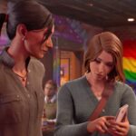 Frau zeigt anderer Frau etwas auf dem Handy in einem Restaurant mit der Regenbogenflagge.